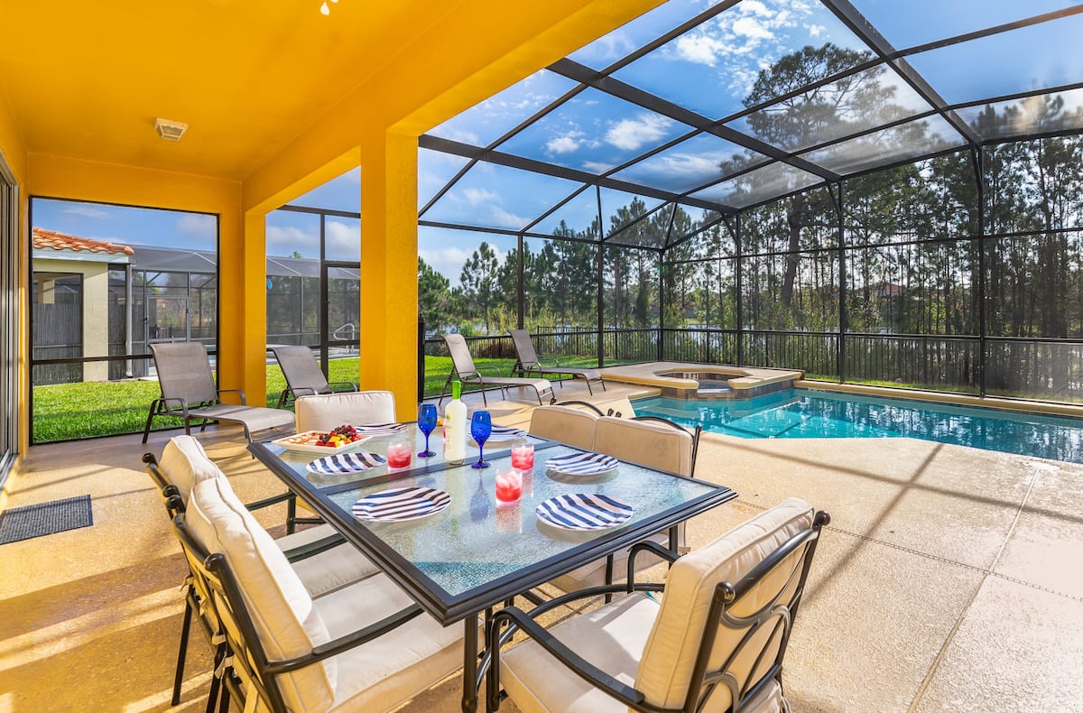 A view at the pool in an open surrounding with a table in front.